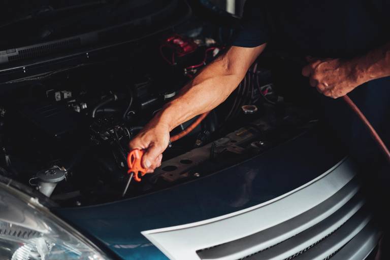 man repairing checking car